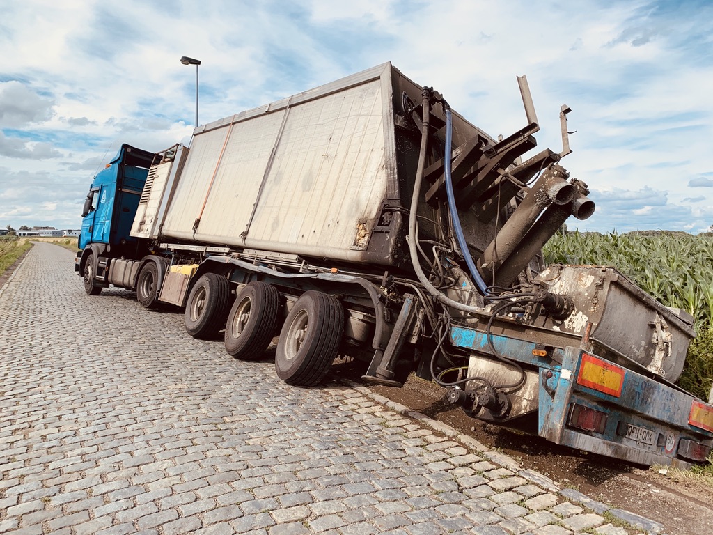 Zware vrachtwagen zakt weg in berm